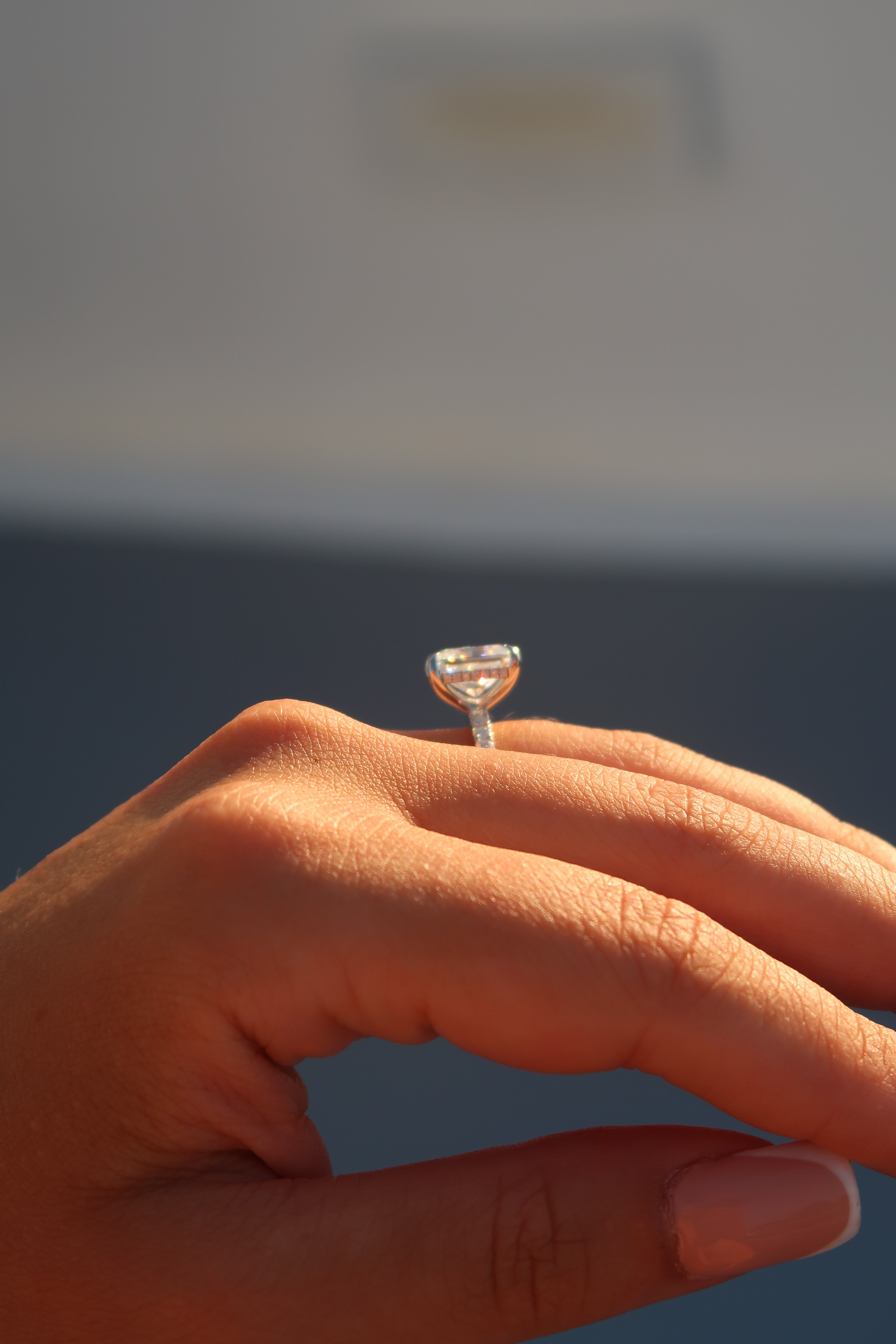 Close-up of radiant cut moissanite engagement ring on finger showing step cut faceting and hidden halo detail
