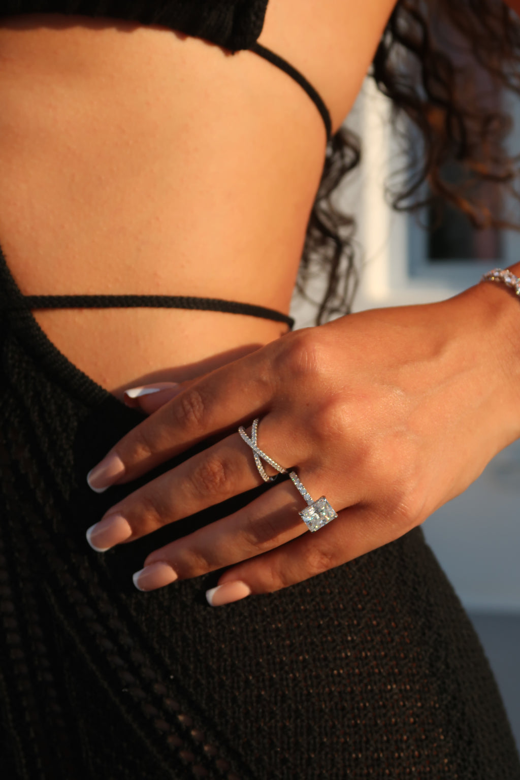 Radiant cut moissanite engagement ring worn on hand against dark clothing showcasing brilliant sparkle