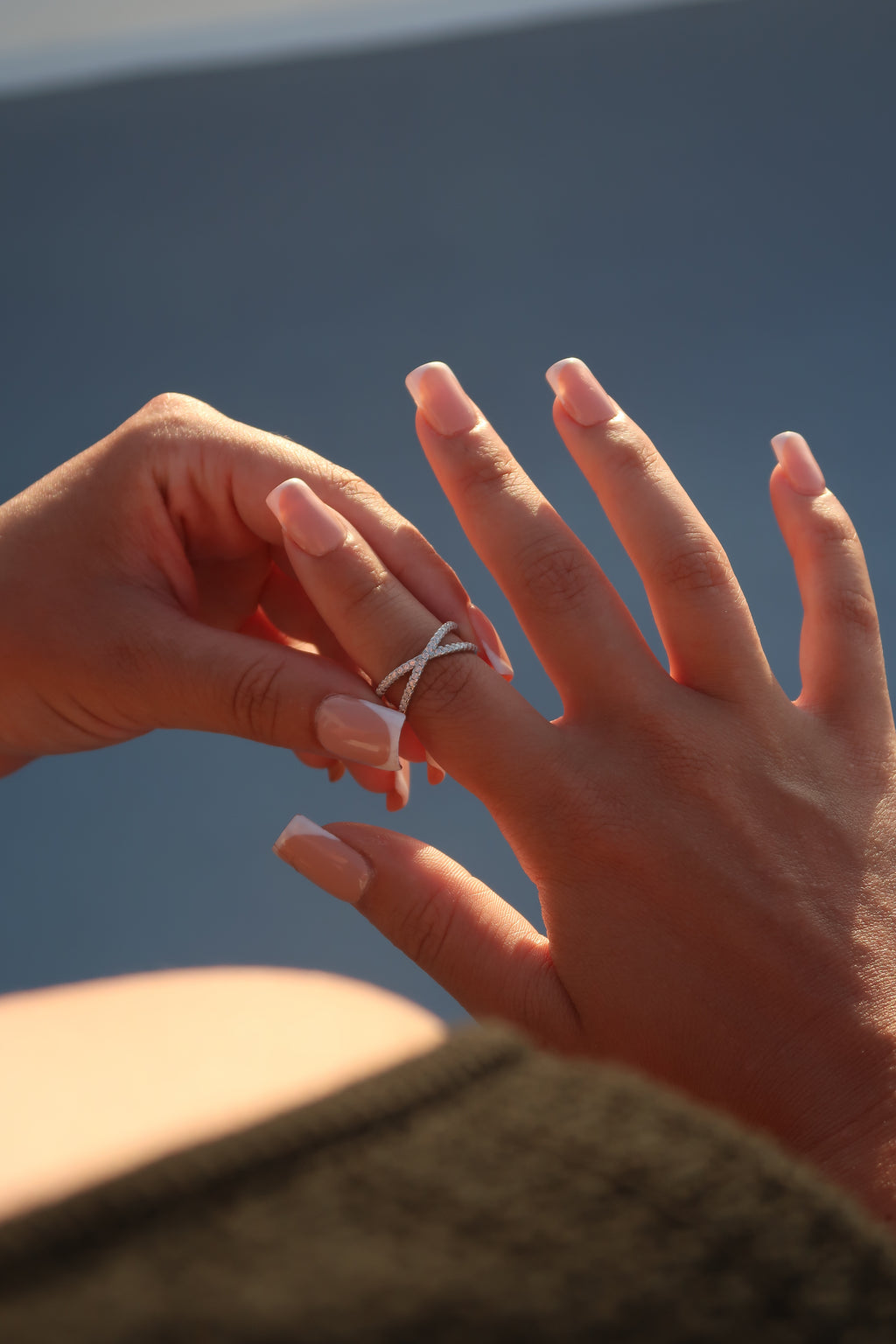 Hand wearing infinity crossover pavé moissanite band in natural sunlight highlighting brilliant sparkle and elegant crossover design