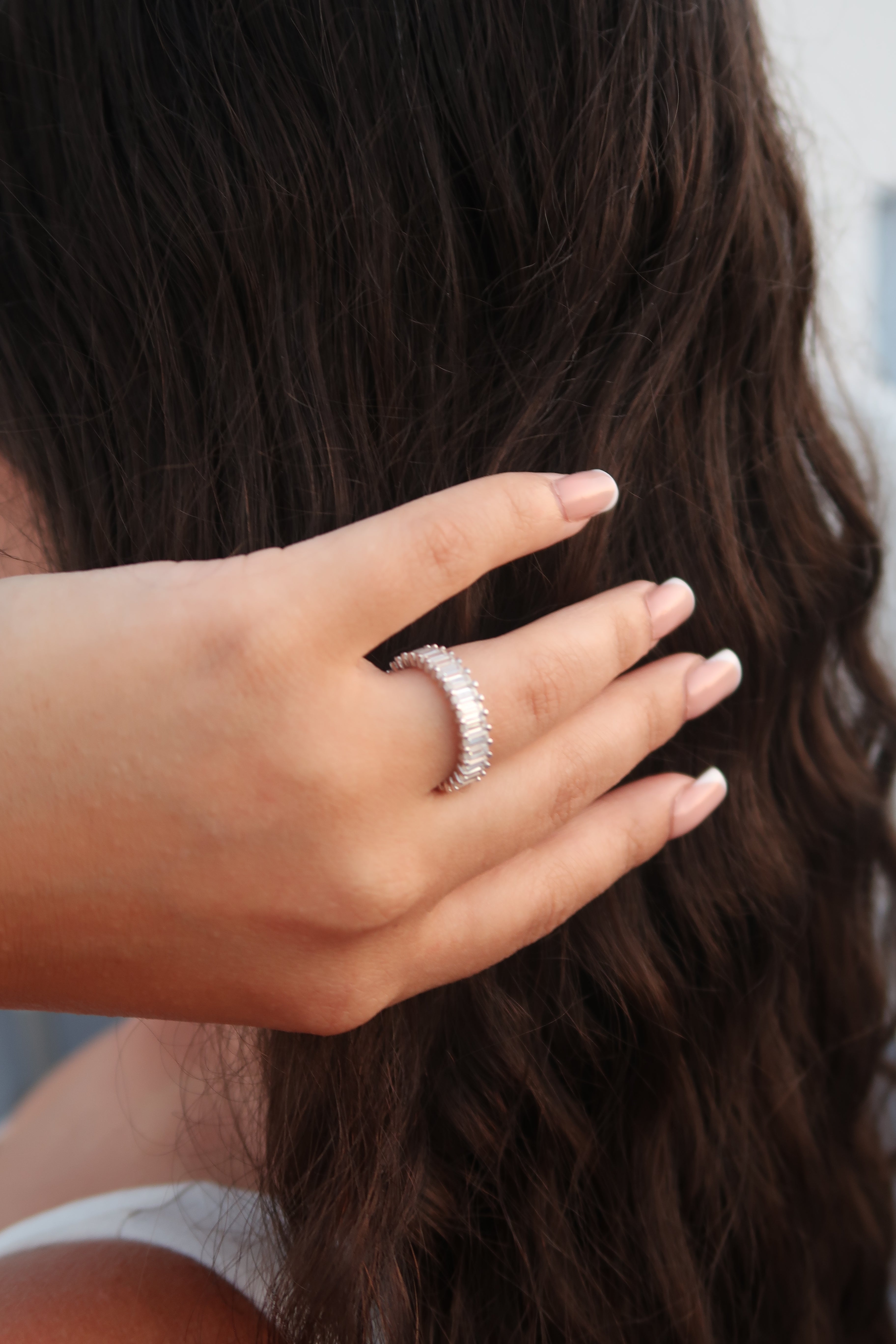 Hand with baguette cut moissanite eternity band running through hair demonstrating luxurious lifestyle styling