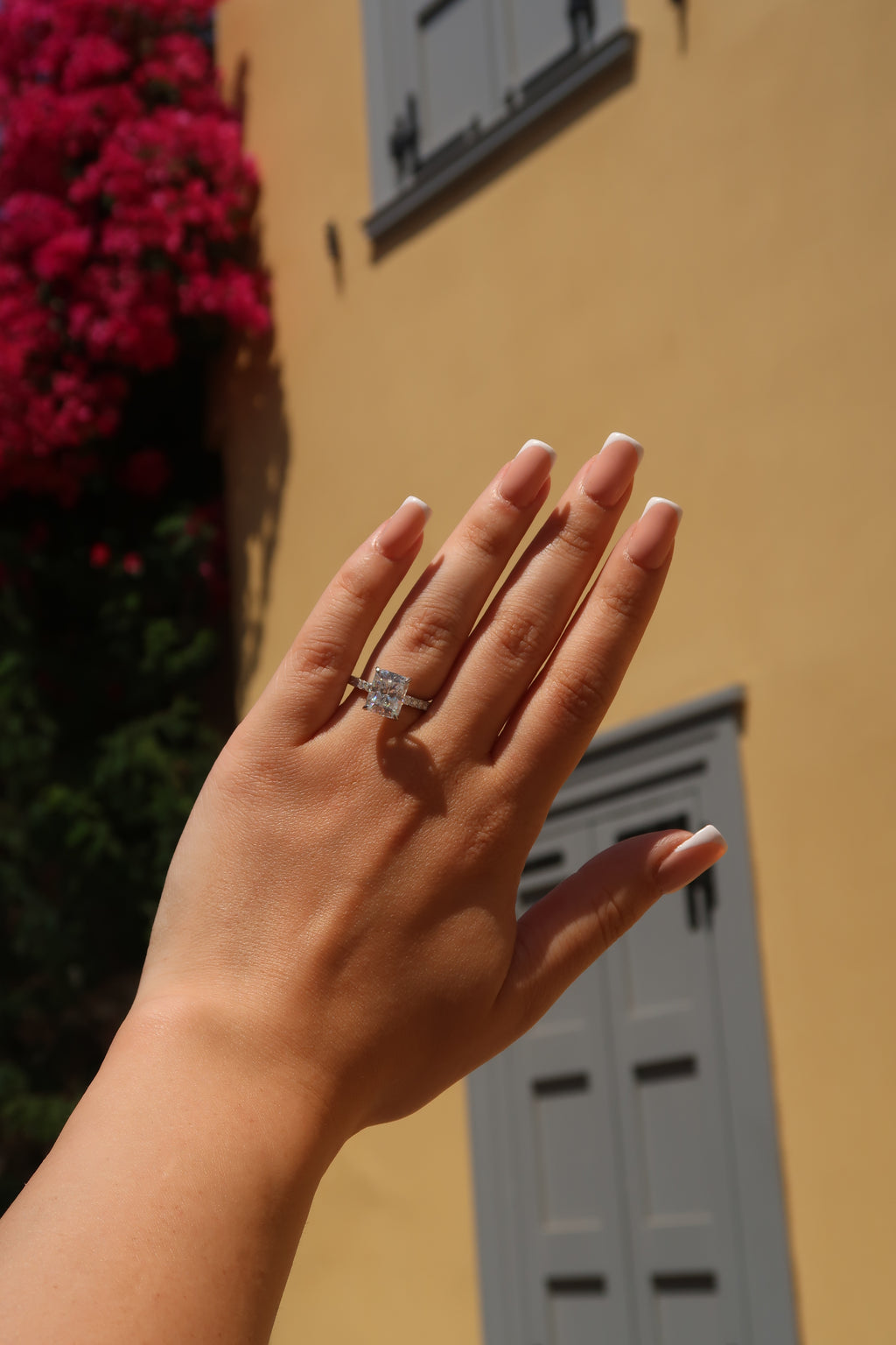 Hand with radiant cut moissanite engagement ring against colorful background showcasing versatile styling