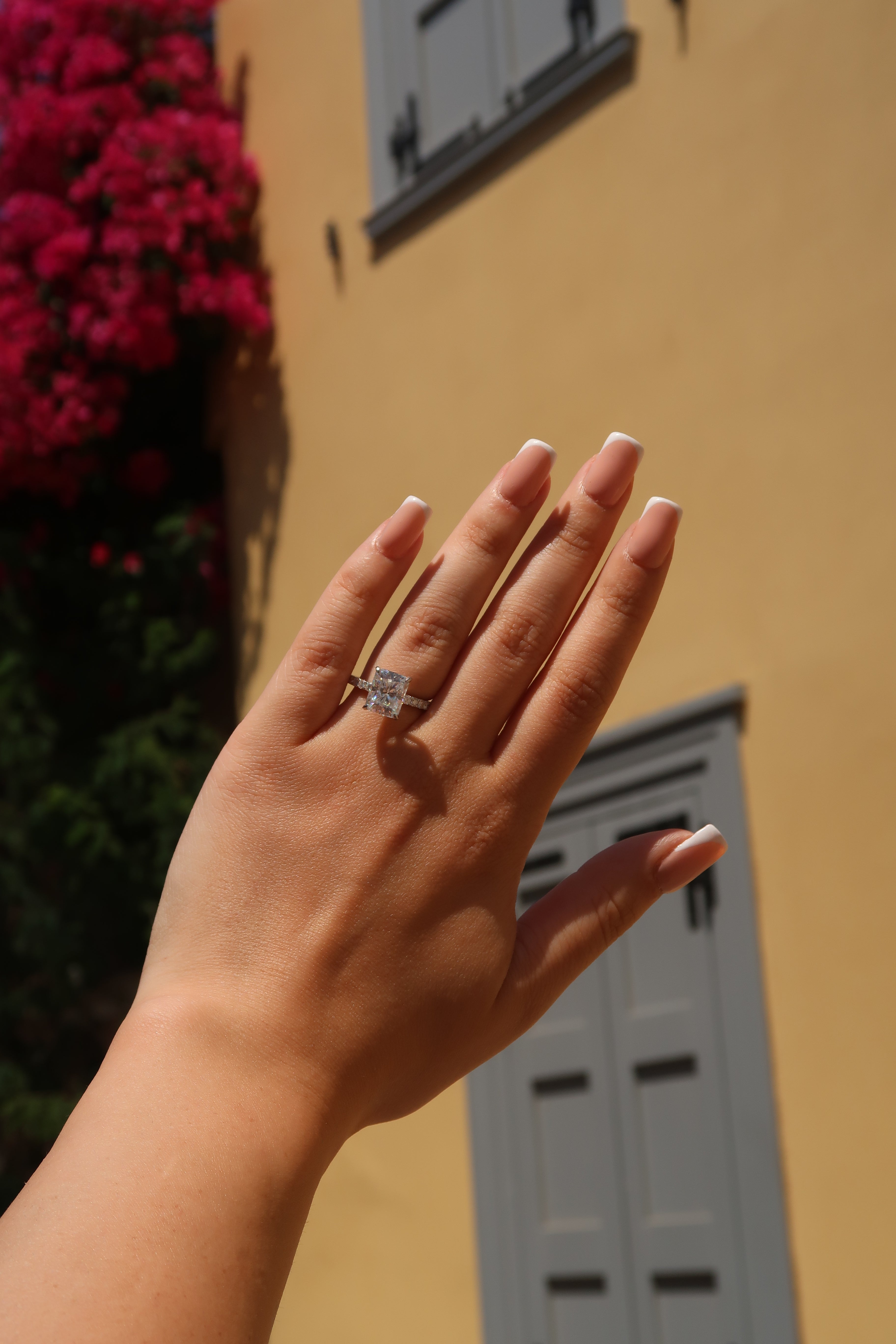 Hand with radiant cut moissanite engagement ring against colorful background showcasing versatile styling