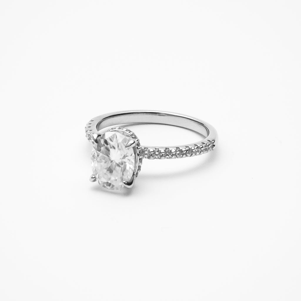 Oval cut moissanite engagement ring with pavé band in white gold setting on clean white background showcasing brilliant center stone and sparkling accents