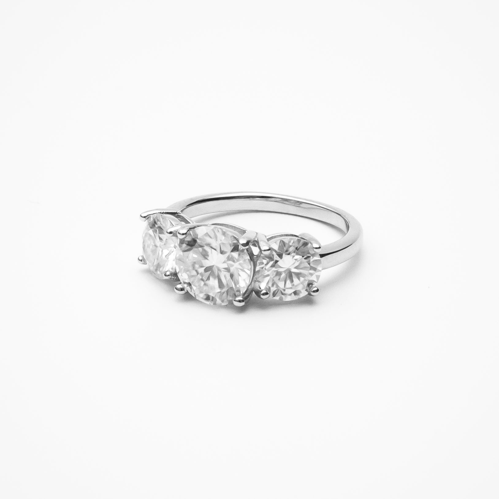 Round cut moissanite three-stone engagement ring in white gold setting on clean white background showcasing past present future design