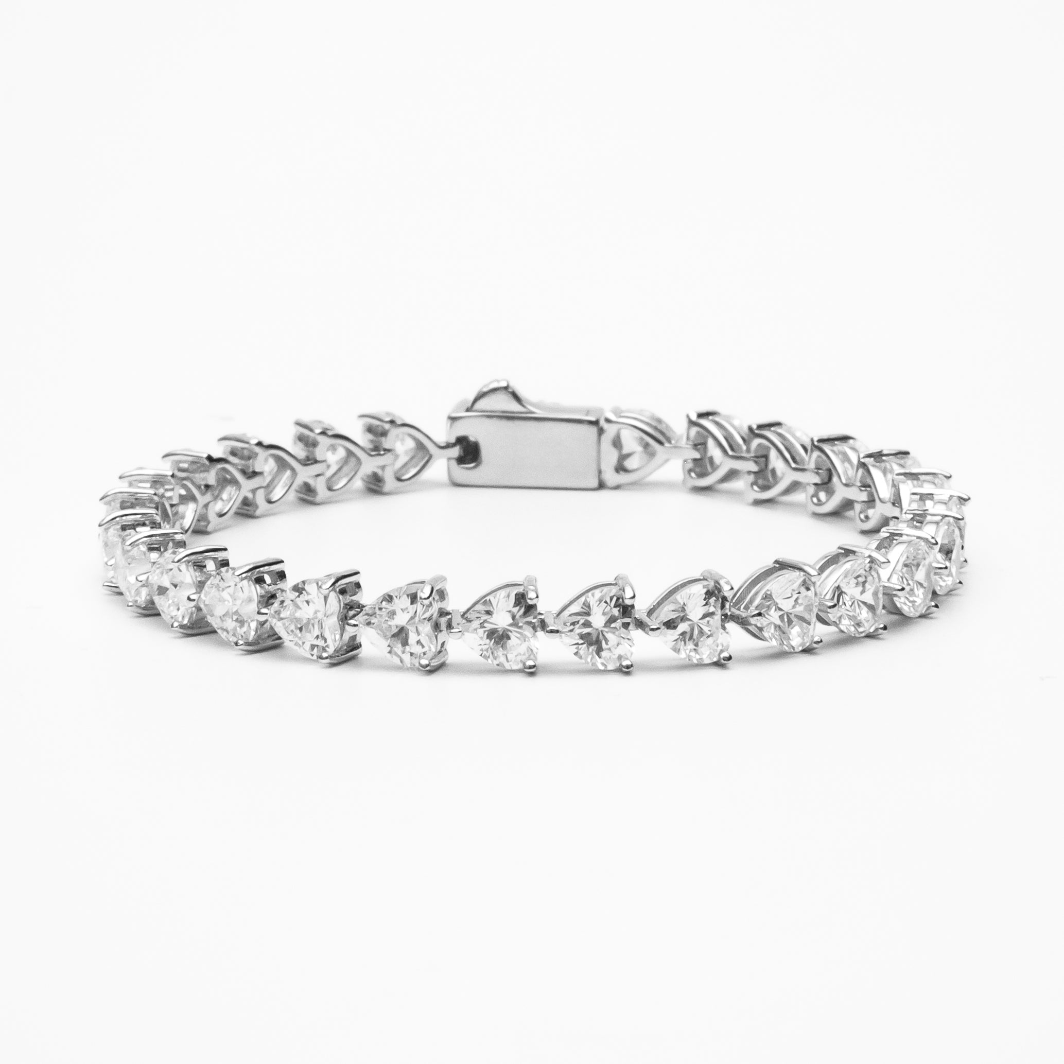 Heart cut moissanite tennis bracelet with continuous line of heart-shaped stones in white gold setting on clean white background