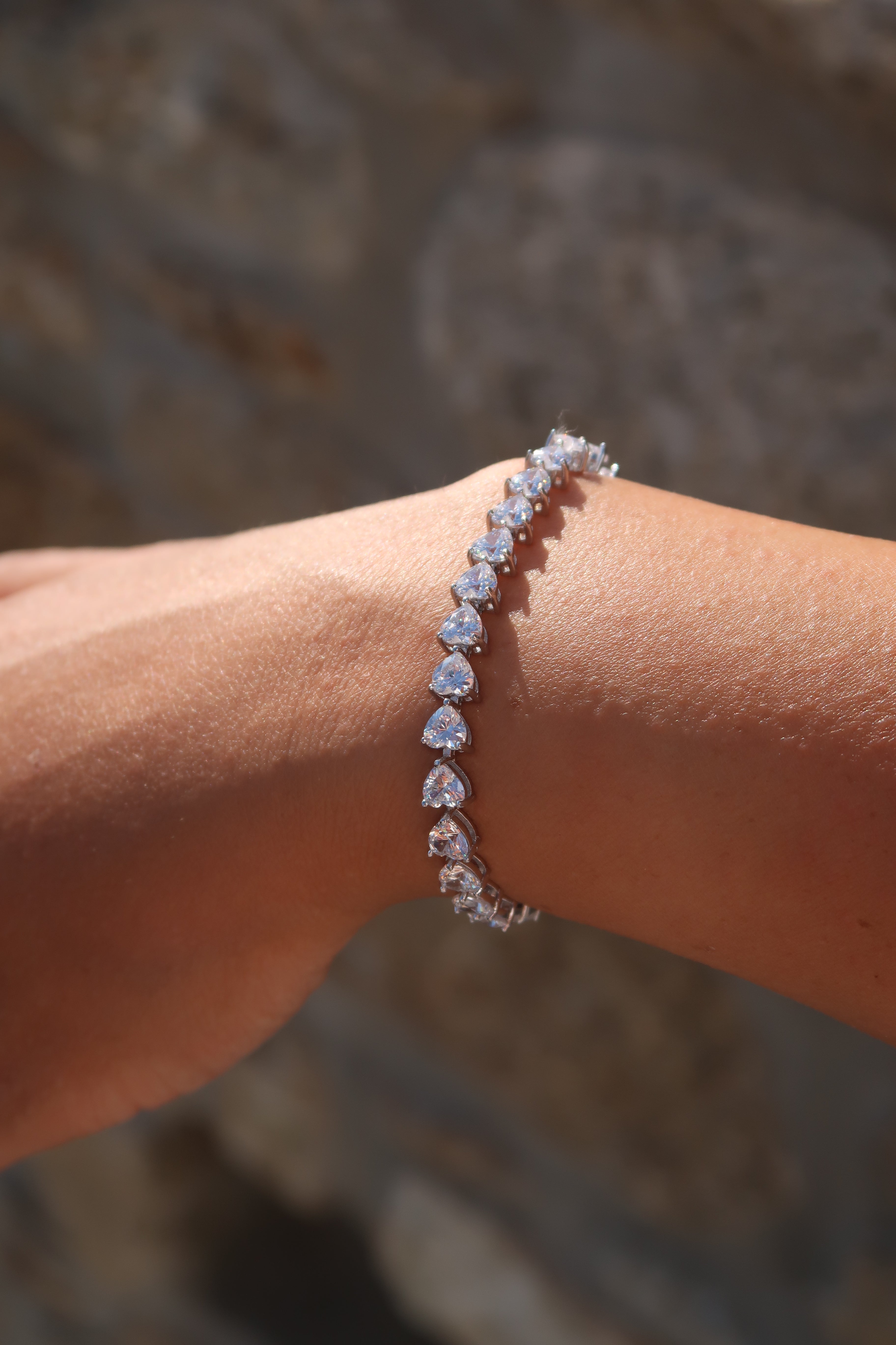 Heart cut moissanite tennis bracelet on wrist in soft lighting showing delicate heart stone details