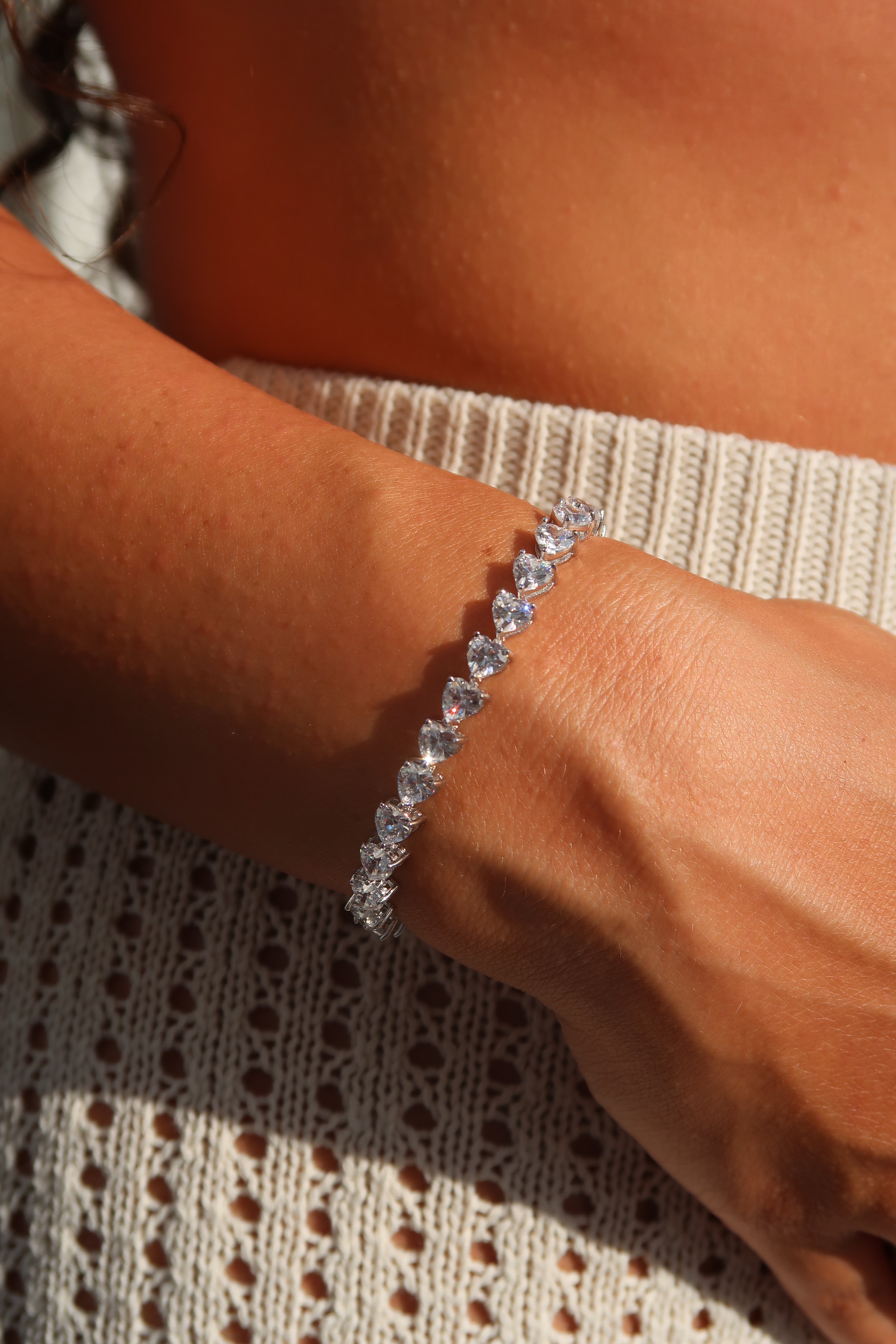 Heart cut moissanite tennis bracelet worn on wrist in natural sunlight showcasing romantic heart-shaped stones