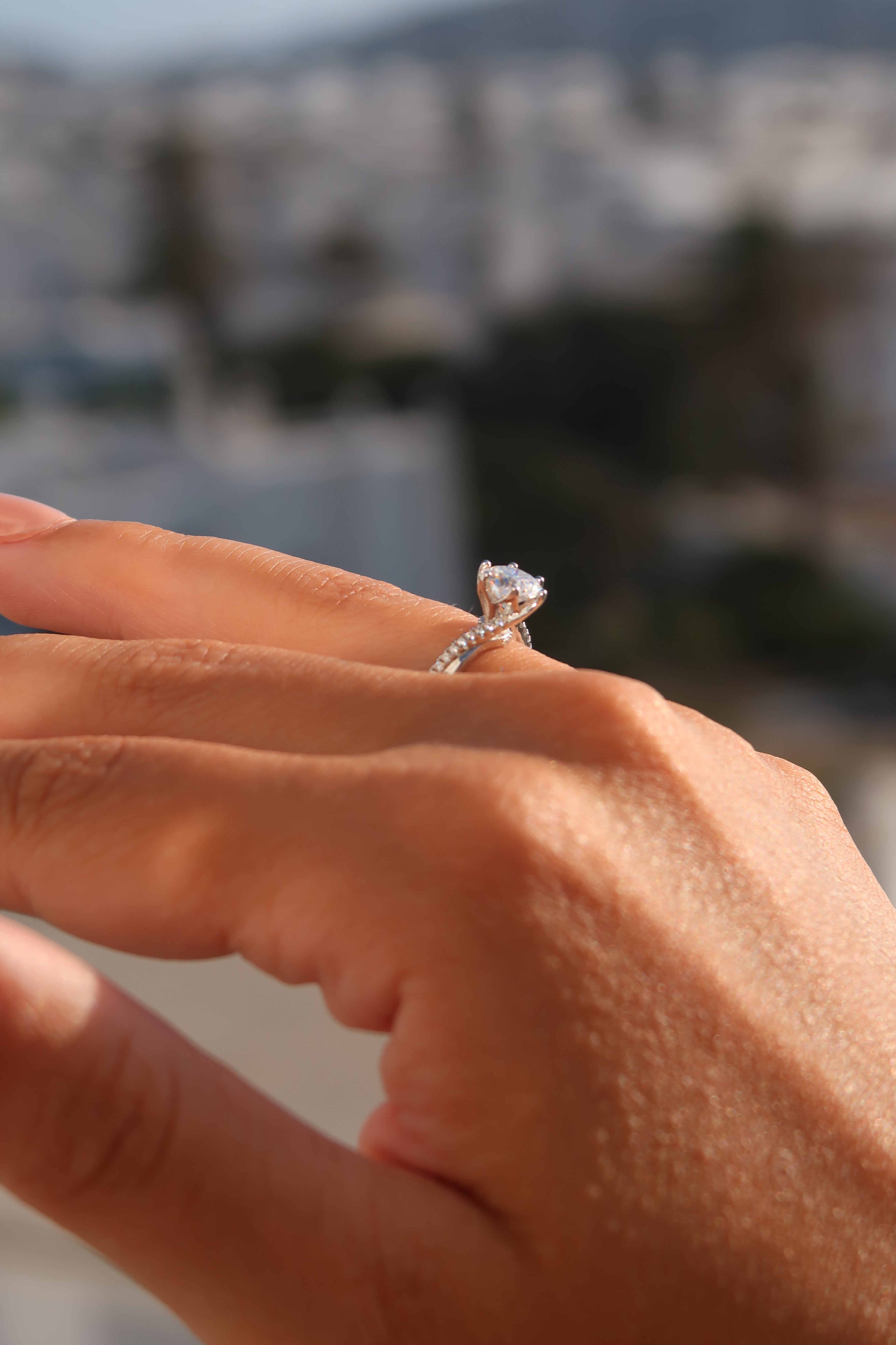 Close-up of hand wearing round cut moissanite engagement ring showing detailed twisted band craftsmanship