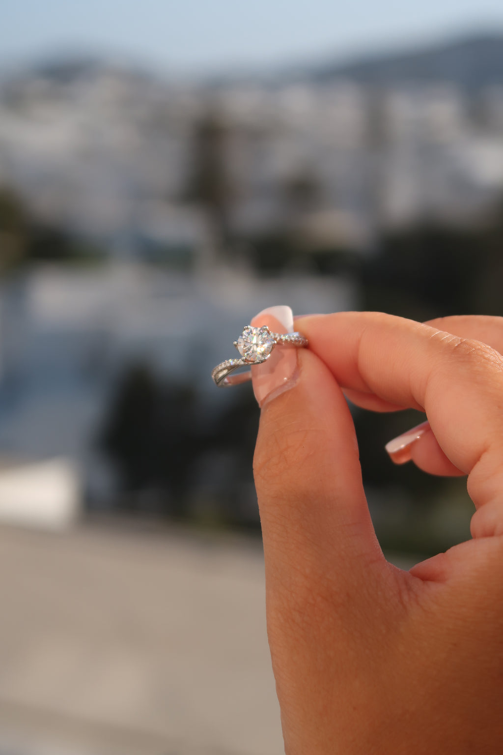Hand wearing round cut moissanite engagement ring in natural setting showcasing timeless twisted design