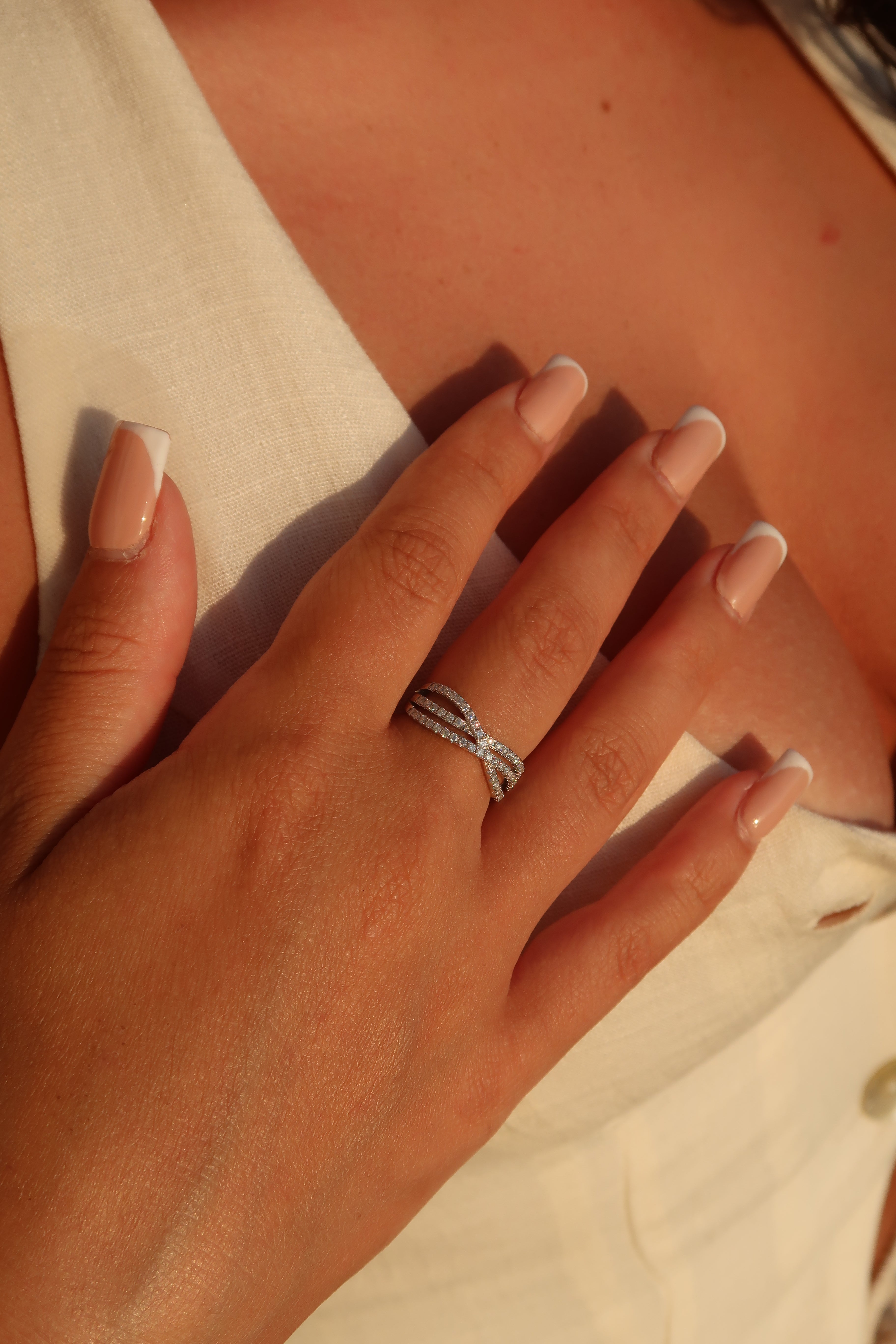 Hands displaying crossover pavé moissanite band in natural lighting highlighting sparkle and movement