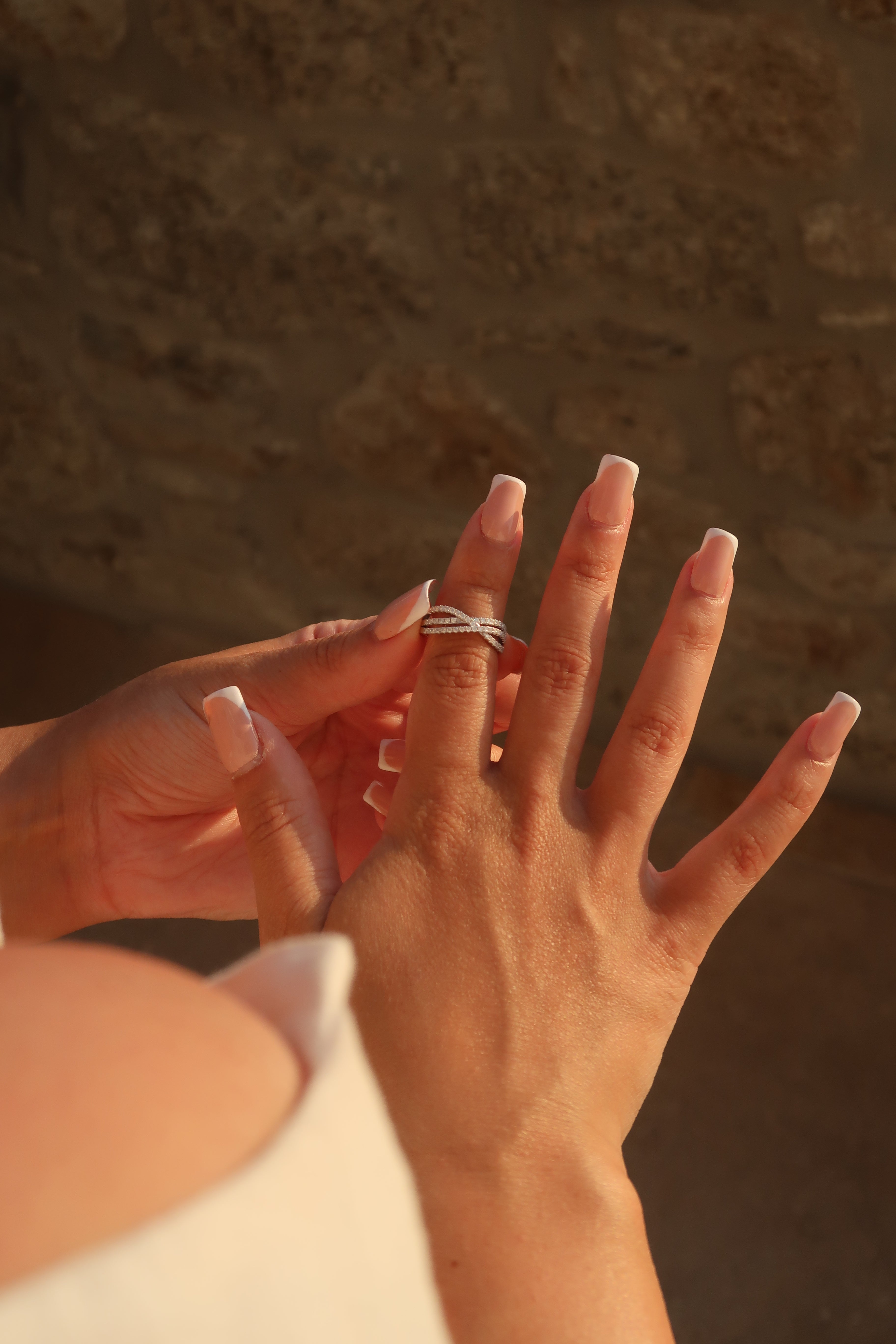 Hand wearing crossover pavé moissanite band in artistic lighting showcasing brilliant stone setting