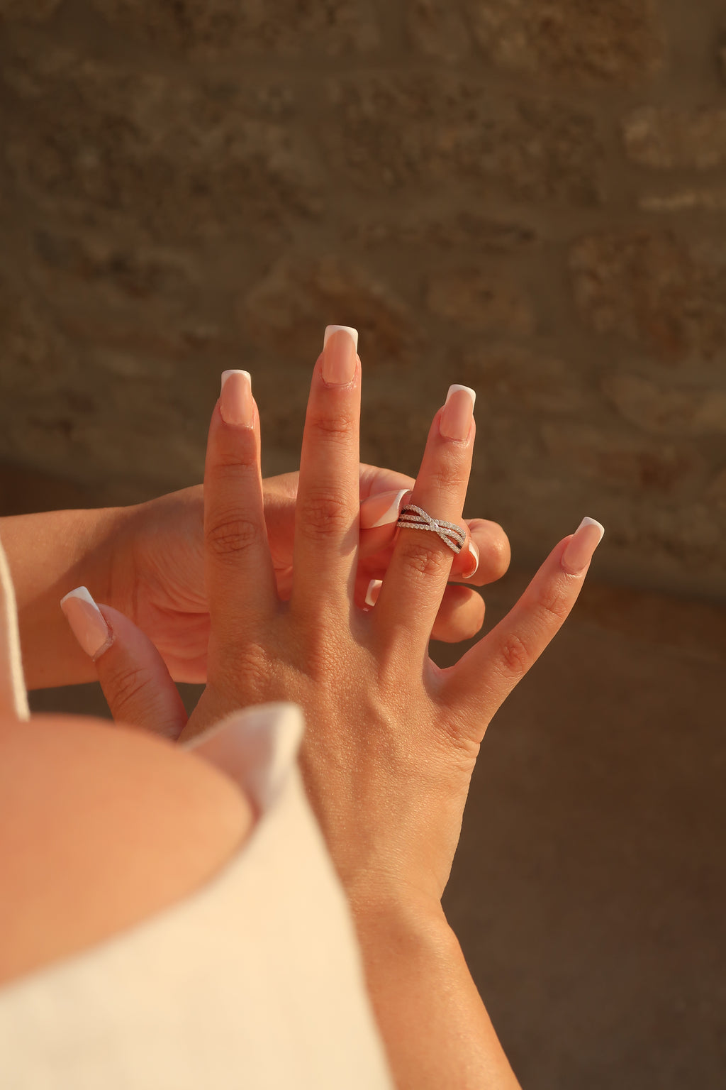 Hand wearing crossover pavé moissanite band with dramatic shadows emphasizing three-band crossover design