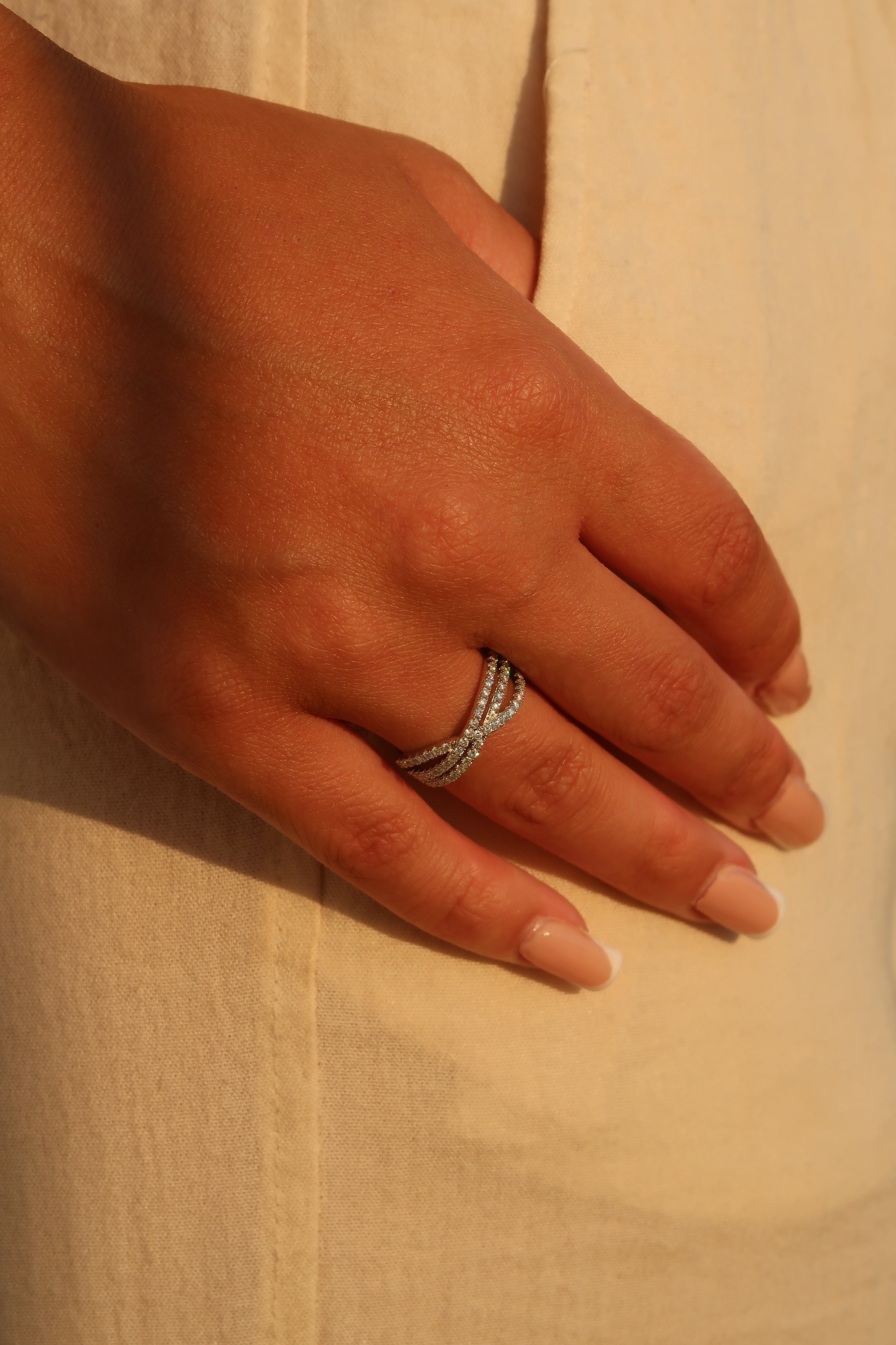 Hand wearing crossover pavé moissanite band on wooden surface showcasing elegant stacking design