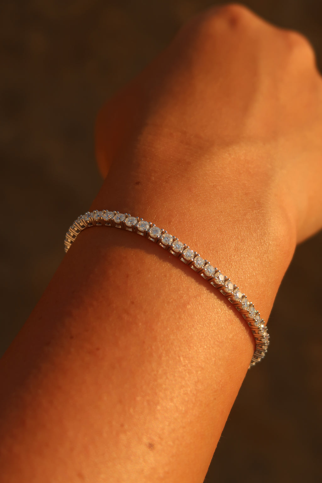 Moissanite tennis bracelet worn on wrist in warm sunlight highlighting brilliant sparkle
