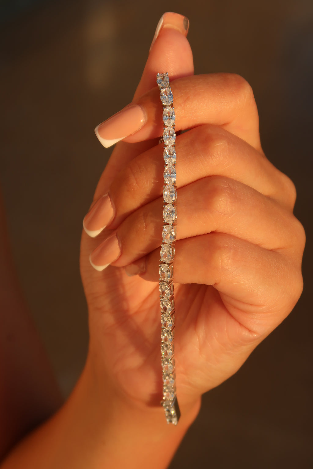 Close-up of hand with oval cut moissanite tennis bracelet showing detailed stone setting and craftsmanship