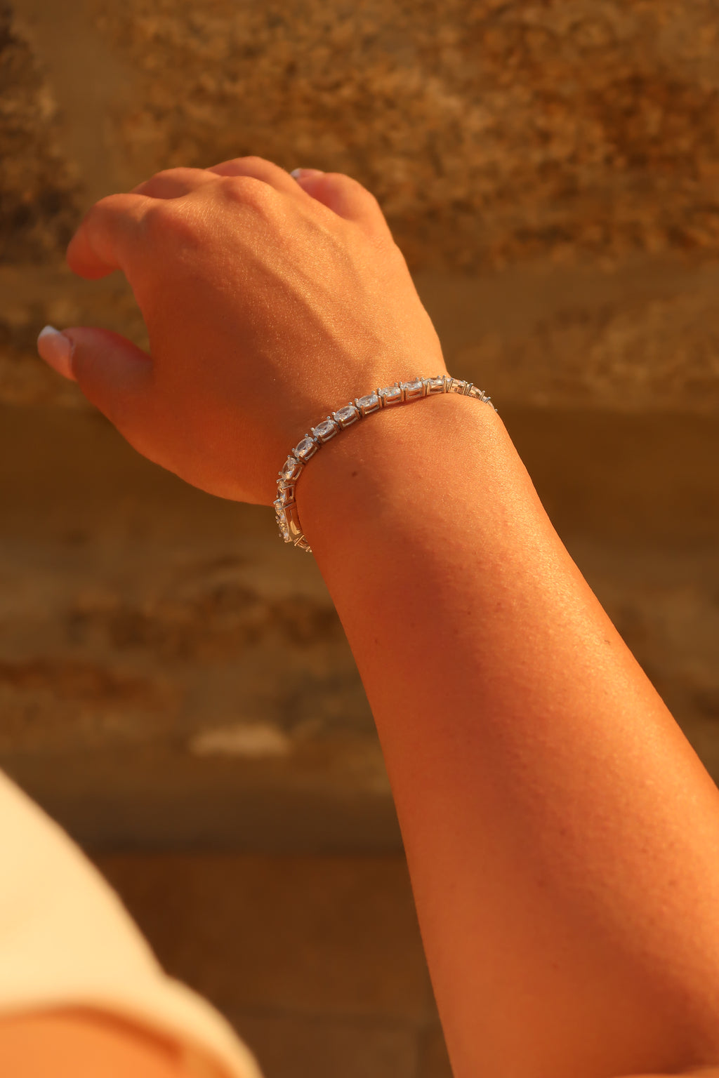 Oval cut moissanite tennis bracelet on wrist showing secure fit and brilliant light reflection