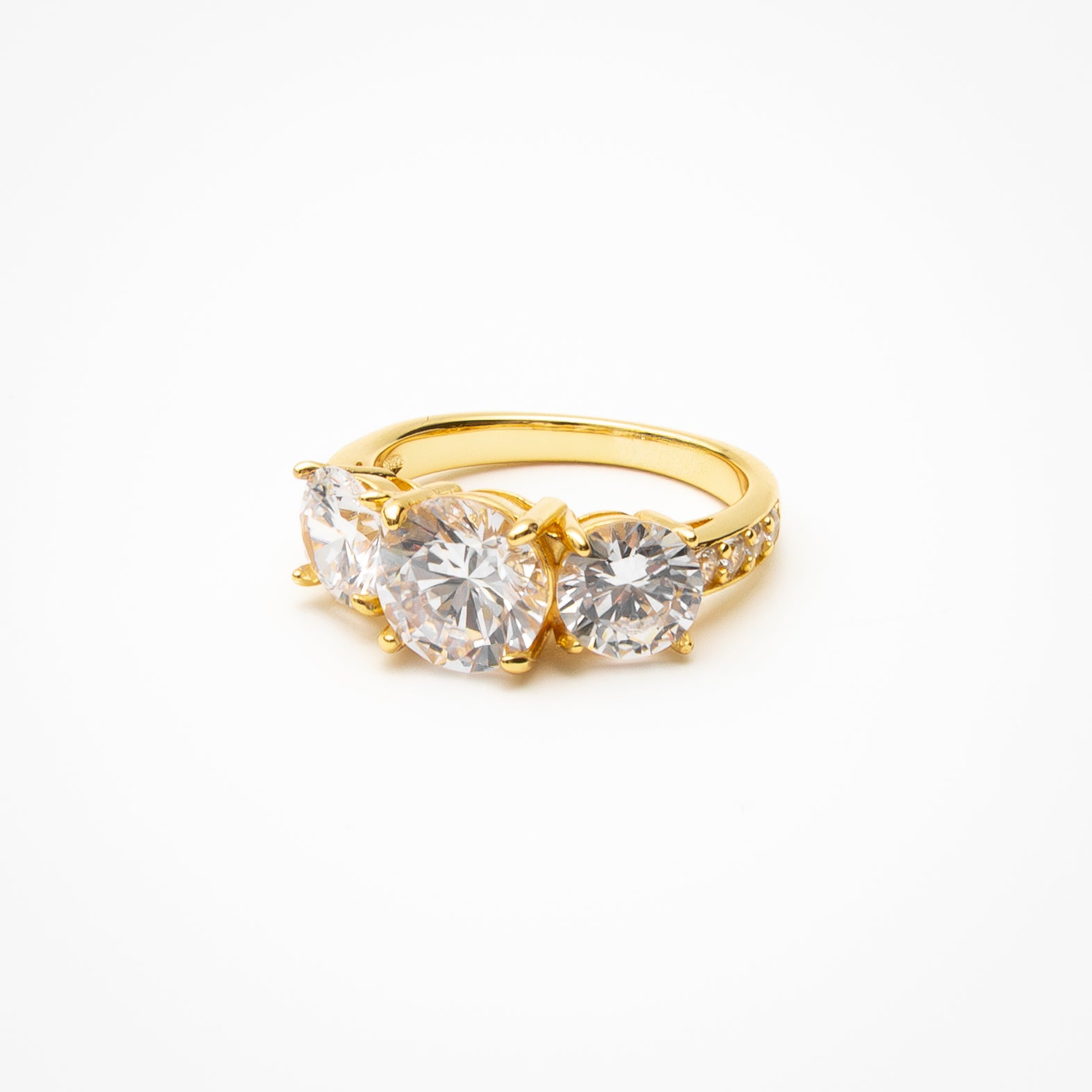 Round cut cubic zirconia three-stone engagement ring with pavé band in yellow gold setting on clean white background showcasing past present future design