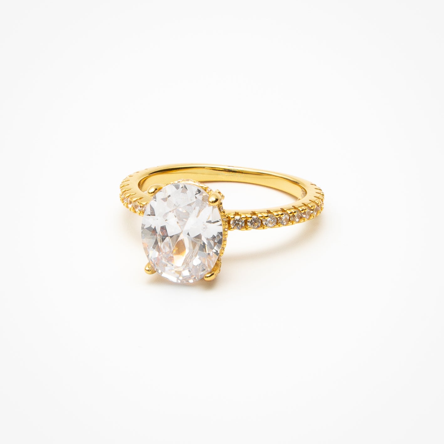 Oval cut cubic zirconia engagement ring with hidden halo and pavé band in yellow gold setting on clean white background showcasing brilliant center stone and sparkling details