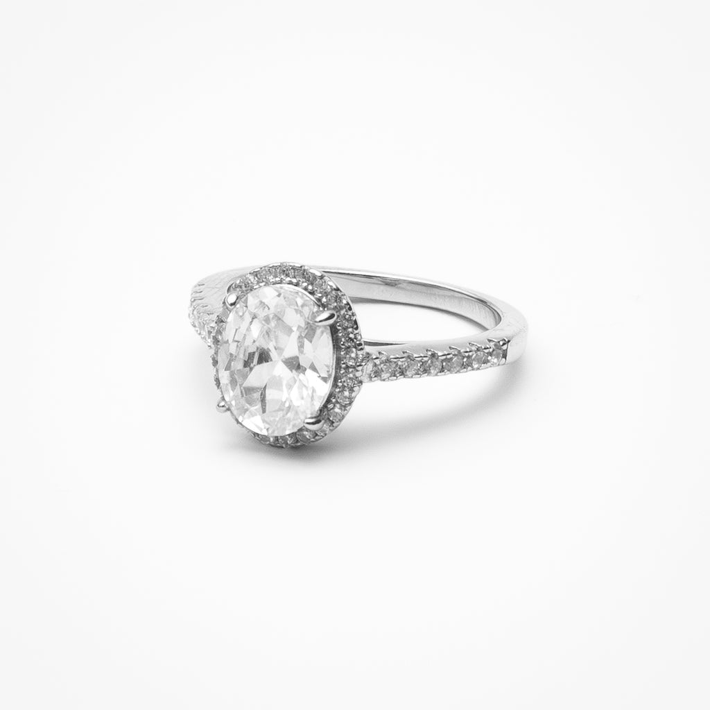 Oval cut cubic zirconia halo engagement ring with pavé band in white gold cathedral setting on clean white background showcasing raised center stone