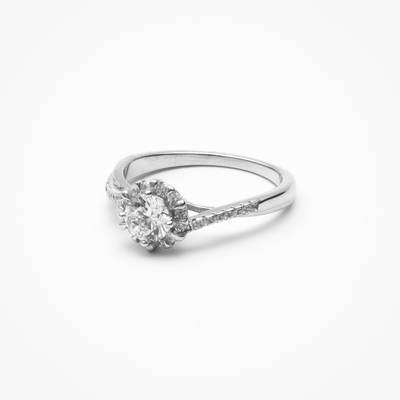 Round cut moissanite halo engagement ring with twisted pavé band in white gold setting on clean white background showcasing six-prong center setting