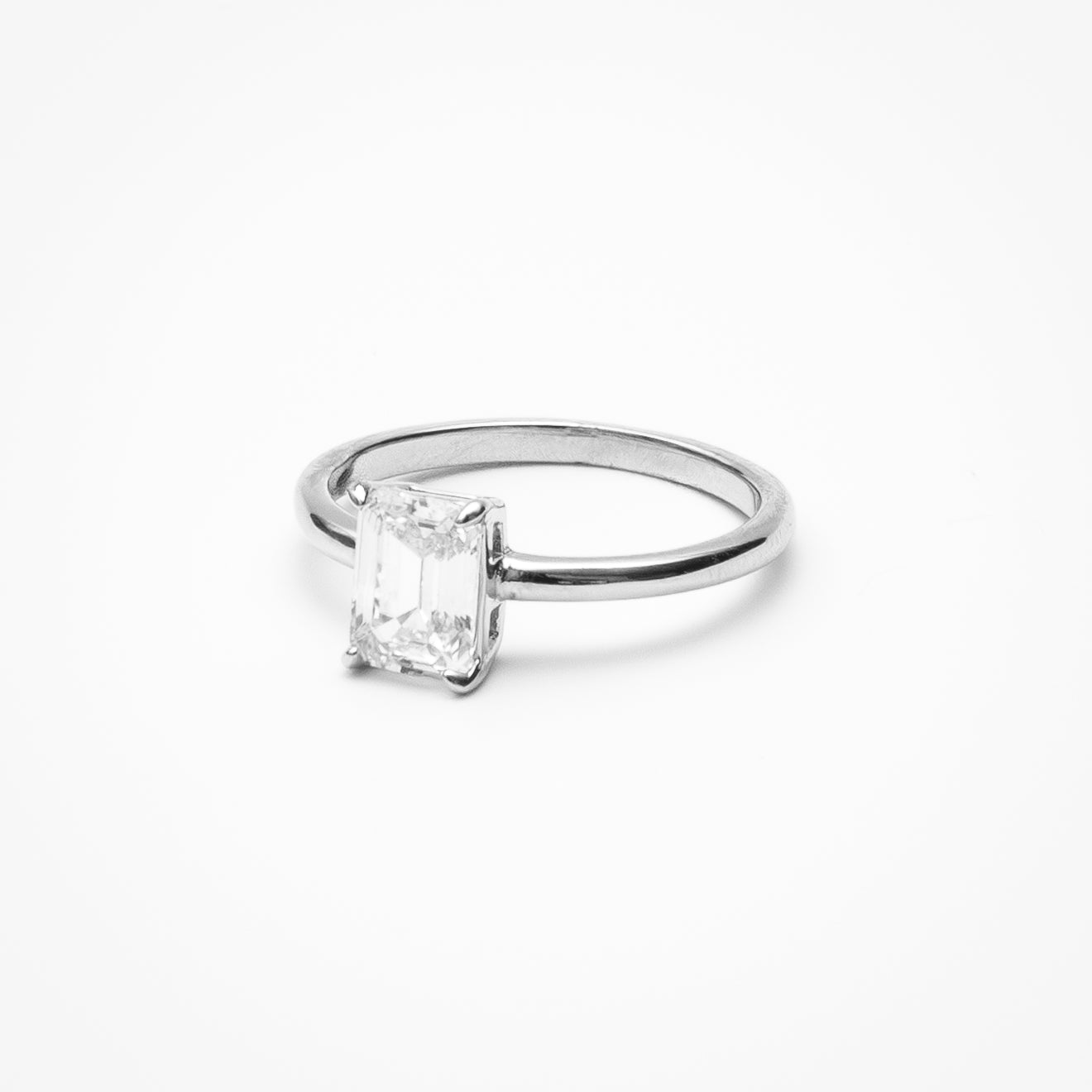 Emerald cut cubic zirconia solitaire engagement ring in white gold setting on clean white background showcasing step cut faceting and low profile design