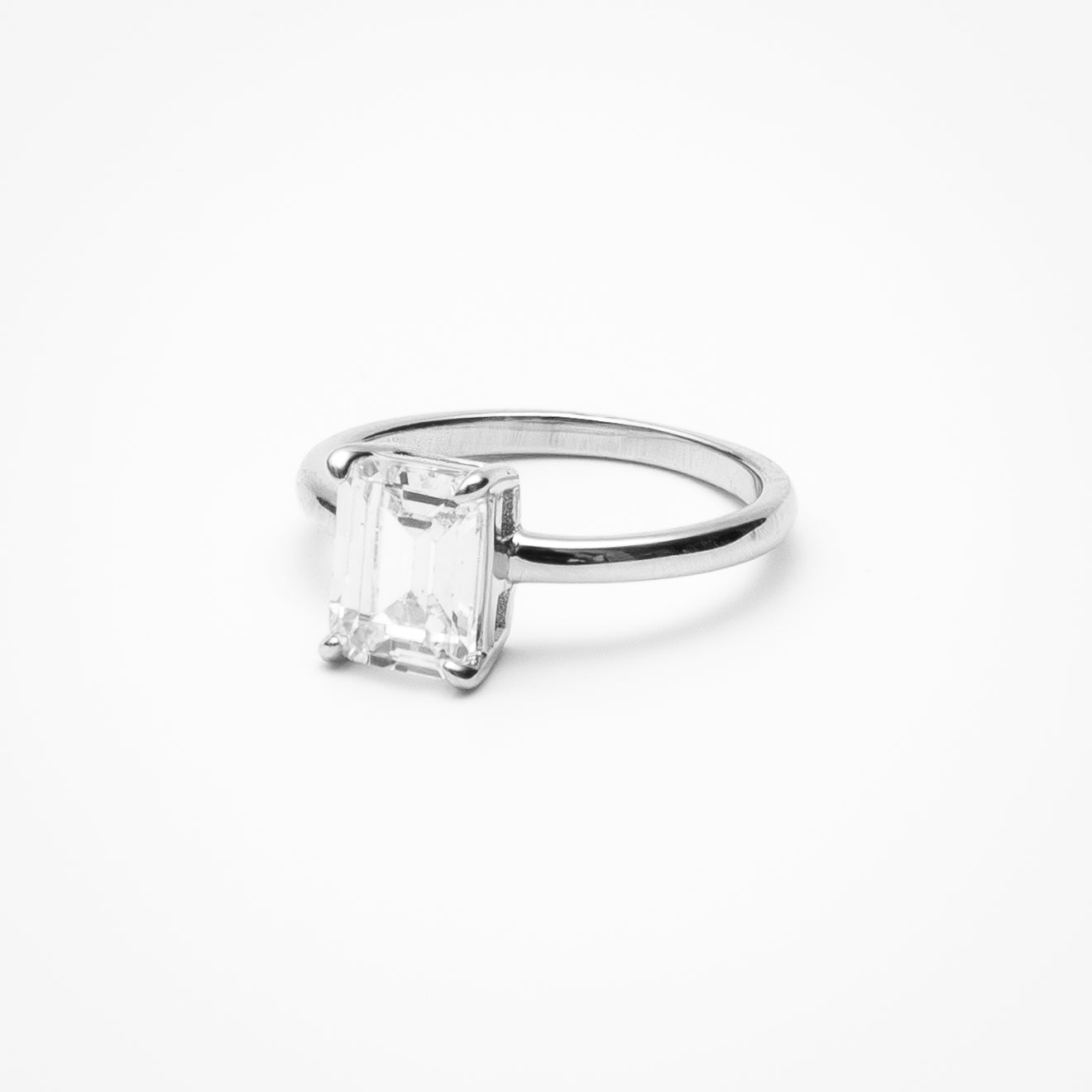 Emerald cut cubic zirconia solitaire engagement ring in white gold setting on clean white background showcasing step cut faceting and low profile design