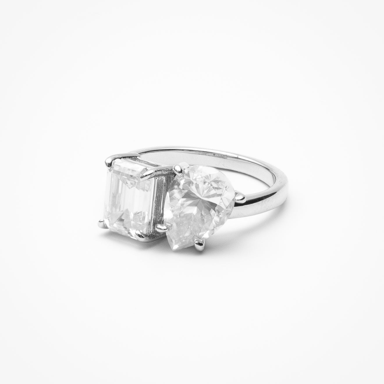 Toi et moi engagement ring with emerald cut and pear cut cubic zirconia stones in white gold setting on clean white background showcasing dual stone design