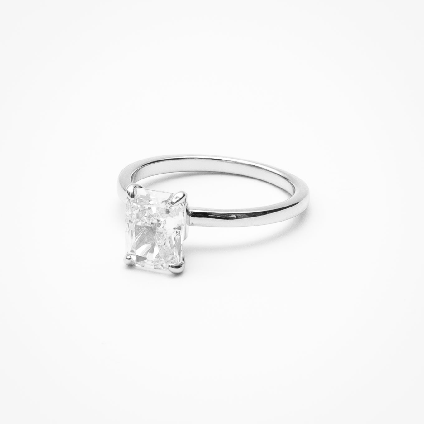 Radiant cut cubic zirconia solitaire engagement ring in white gold setting on clean white background showcasing step cut faceting and low profile design