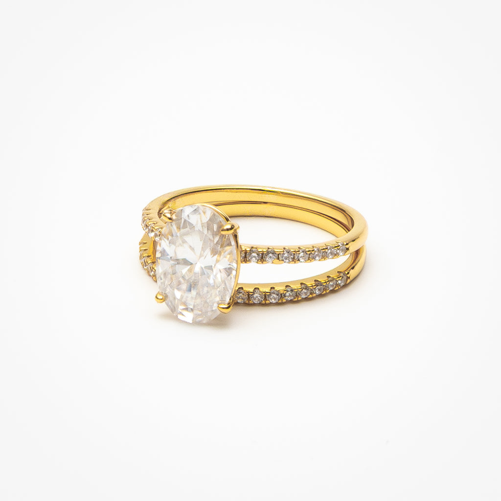 Oval cut moissanite engagement ring with pavé band and matching eternity wedding band in yellow gold setting on clean white background showcasing bridal set