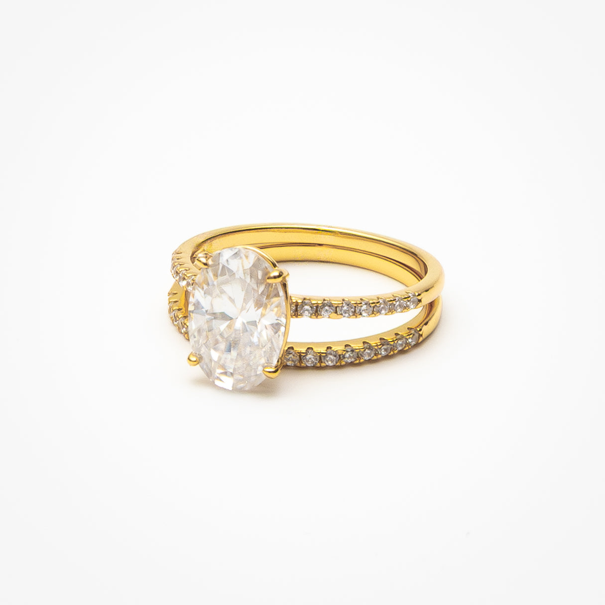 Oval cut moissanite engagement ring with pavé band and matching eternity wedding band in yellow gold setting on clean white background showcasing bridal set