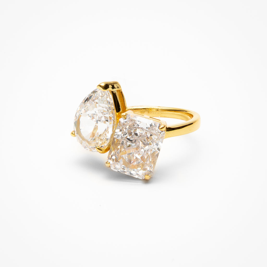 Toi et moi engagement ring with pear cut and radiant cut cubic zirconia stones in yellow gold setting on clean white background showcasing dual stone design