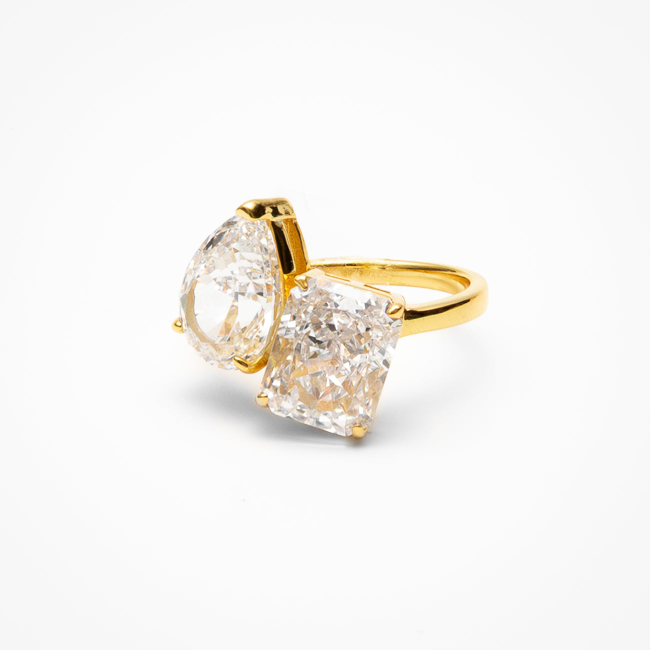 Toi et moi engagement ring with pear cut and radiant cut cubic zirconia stones in yellow gold setting on clean white background showcasing dual stone design