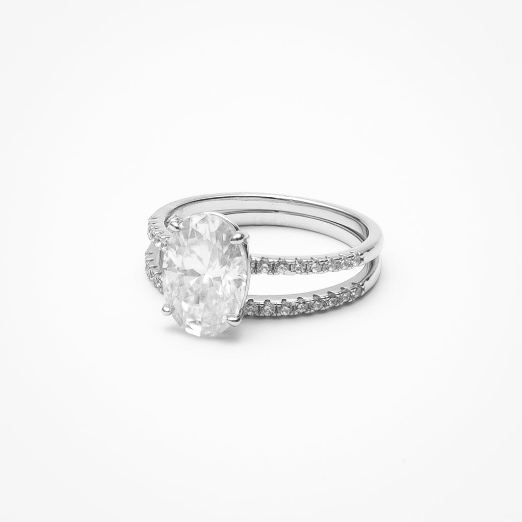 Oval cut moissanite engagement ring with pavé band and matching eternity wedding band in white gold setting on clean white background showcasing bridal set