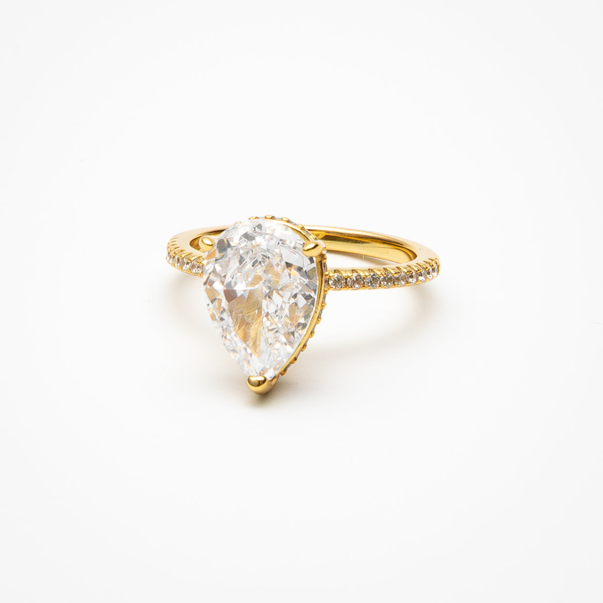 Pear cut cubic zirconia engagement ring with hidden halo and pavé band in yellow gold setting on clean white background showcasing teardrop shape and sparkling details