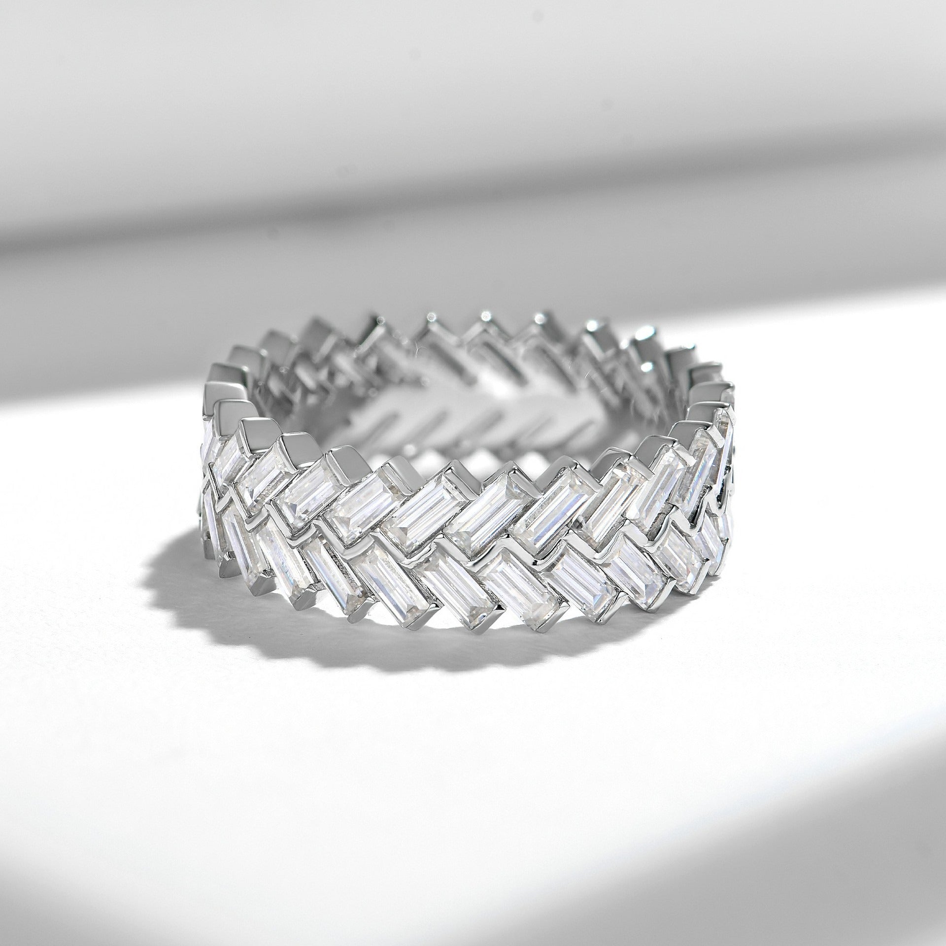 Baguette cut moissanite eternity band with interwoven basketweave pattern in white gold setting on clean white background showcasing geometric design and continuous sparkle