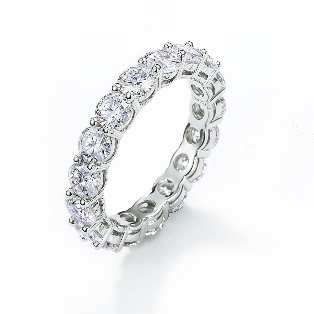 Round cut moissanite eternity band at angle showing depth and brilliant stone setting with shared prong design and sparkling moissanite stones